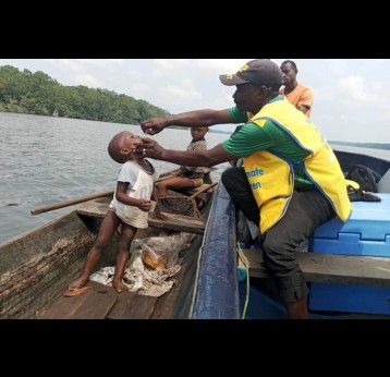 Un agent de santé administre des gouttes de vaccin contre la poliomyélite à un enfant à bord d’une pirogue dans une zone difficile d’accès du bassin du lac Tchad. La campagne vise à atteindre tous les enfants, même dans les zones les plus reculées. Crédit : PEV Cameroun