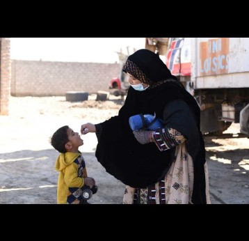 A female health worker administering polio drops to a girl during a door to door immunisation campaign. Credit: Emergency Operation Centre Khyber Pakhtunkhwa. 