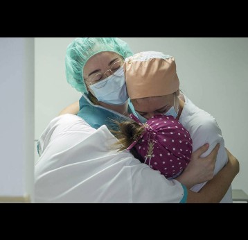 Frontline health workers hug in a hospital corridor. Credit: Europa Press News/ Getty images