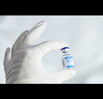 Close-up of a hand holding a blue and white vial of an mRNA-based COVID-19 vaccine. Credit: Spencer Davis on Unsplash