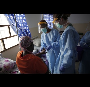 Health workers check the hands of an mpox patient at a treatment centre in Freetown. Credit: Saidu Bah