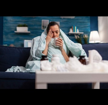 Sick woman sitting at home in blanket with hot tea. Credit: DC Studio/Freepik