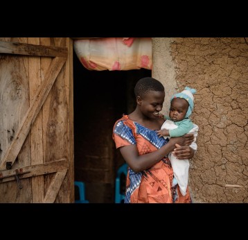 Leah Nagudi poses with her child at their house in Kikolo village. Credit: PATH, Robert Kayemba
