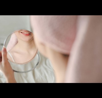 Young woman smiling, looking in the mirror. Photo by Galina Kondratenko on Unsplash
