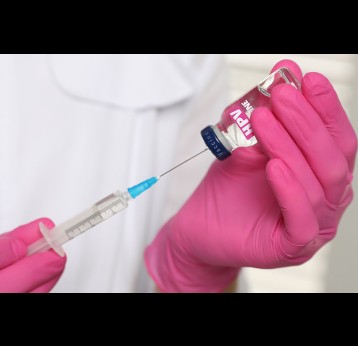 HPV vaccine. Healthcare worker with vial and syringe, closeup.