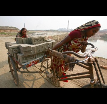 Climate refugees Rabeya Khatoon, right, and Moriom Bibi, who lost their homes to cyclone Aila, work at a brick field on the outskirts of Dhaka in the heat, 2009. Image by AP Photo/Pavel Rahman.