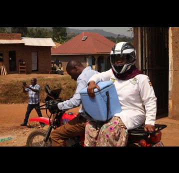 Zaina Namalwa, an enrolled nurse and immunisation focal person going to a second outreach, being riden by a hospital nursing officer. Credit: John Musenze