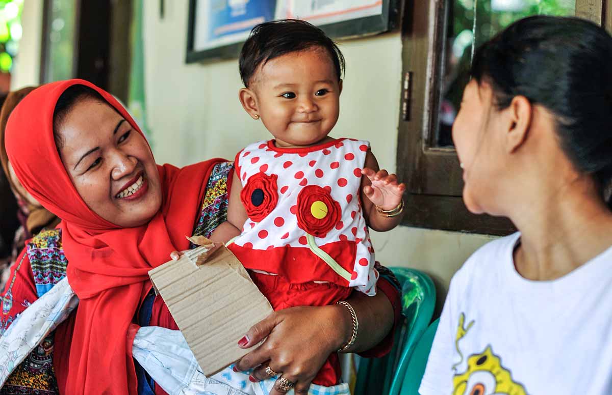 A parent and child with a vaccination card, Indonesia. Credit: Gavi/2013/Chris Stowers.