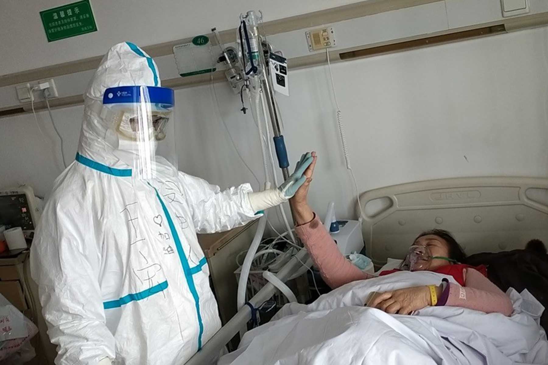 Nurse and patient high five in hospital room - credit: WHO/2020