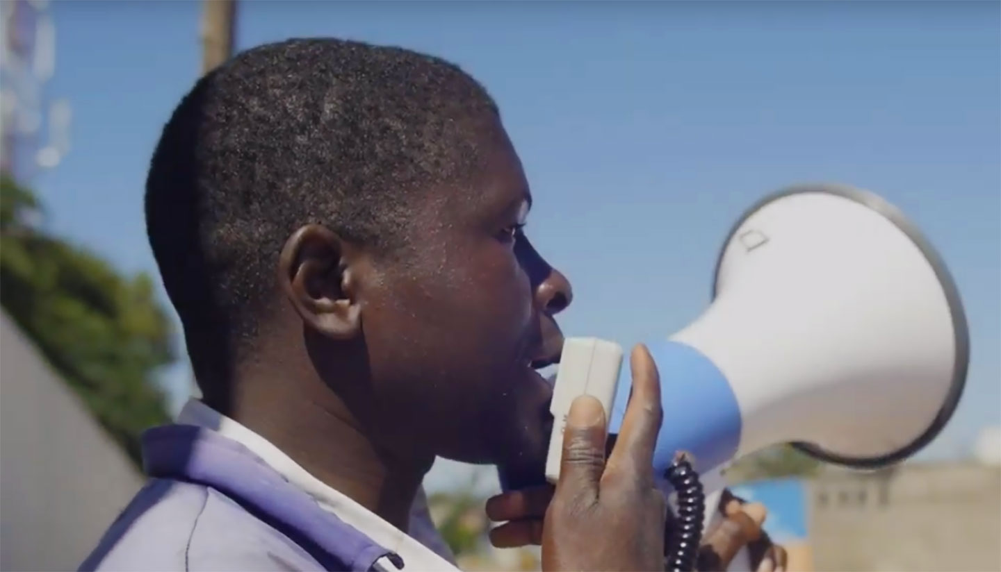 Health worker announcing vaccination session through a megaphone