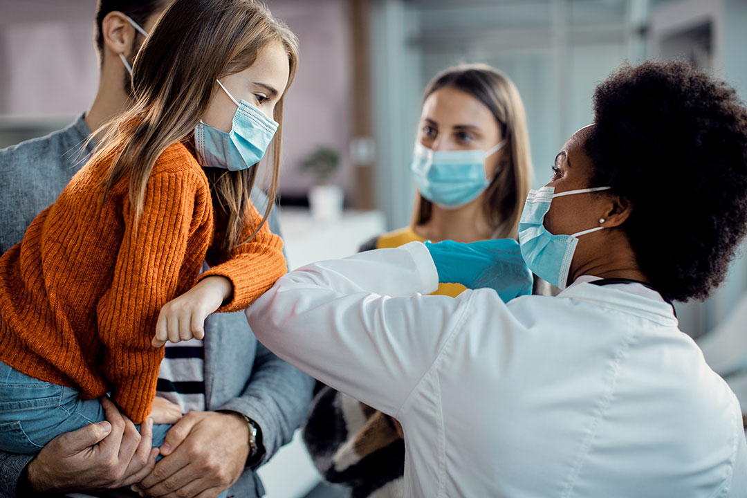 A girl elbow bumping with a paediatrician while greeting at the clinic during coronavirus pandemic.