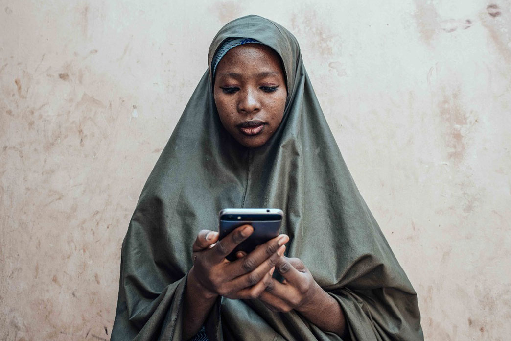 Nigerian woman using her phone. Credit: KC Nwakalor for USAID