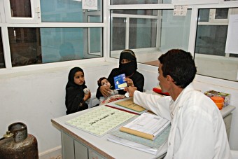 A mother receives a vaccination card for her children at a health centre in Yemen