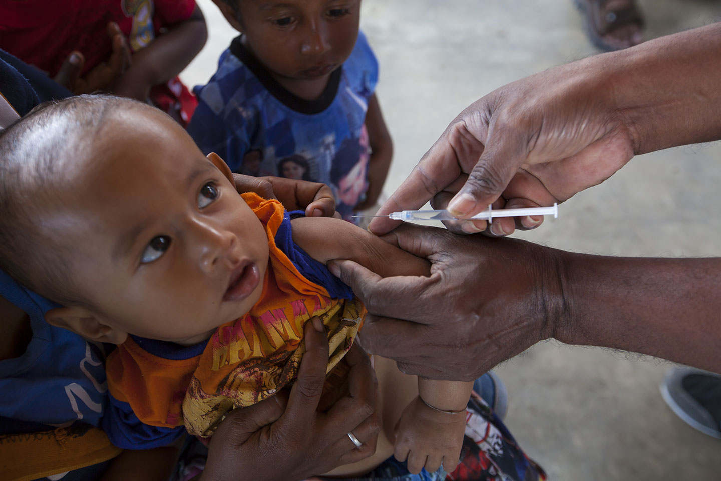 A baby, held tightly by his mother, is vaccinated against measles and rubella in Viqueque Municipality. © UNICEF Timor-Leste/Soares.