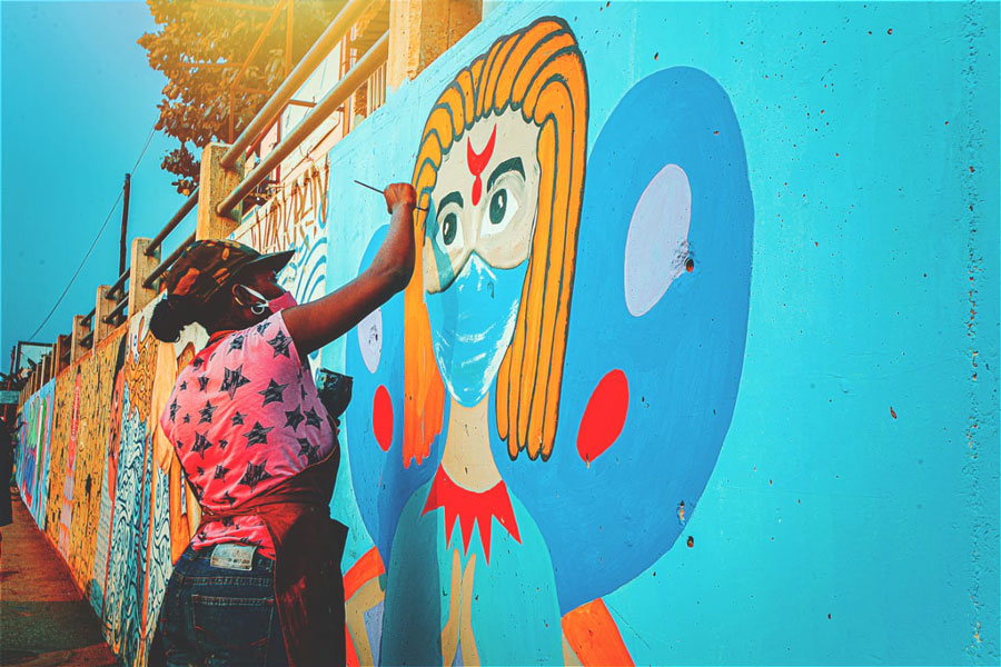 Oksanna Dias working on her mural of an angel on Samba Road, Luanda