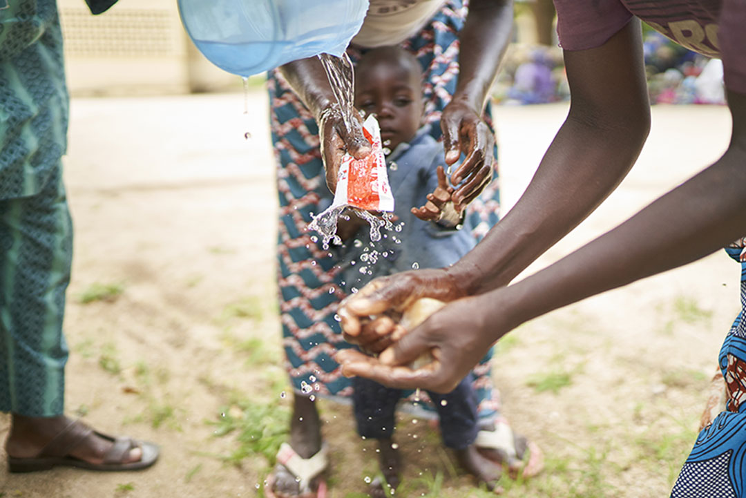 A woman given water to wash her hands with soap – Photographer: Gavi/2020/Christophe Da Silva