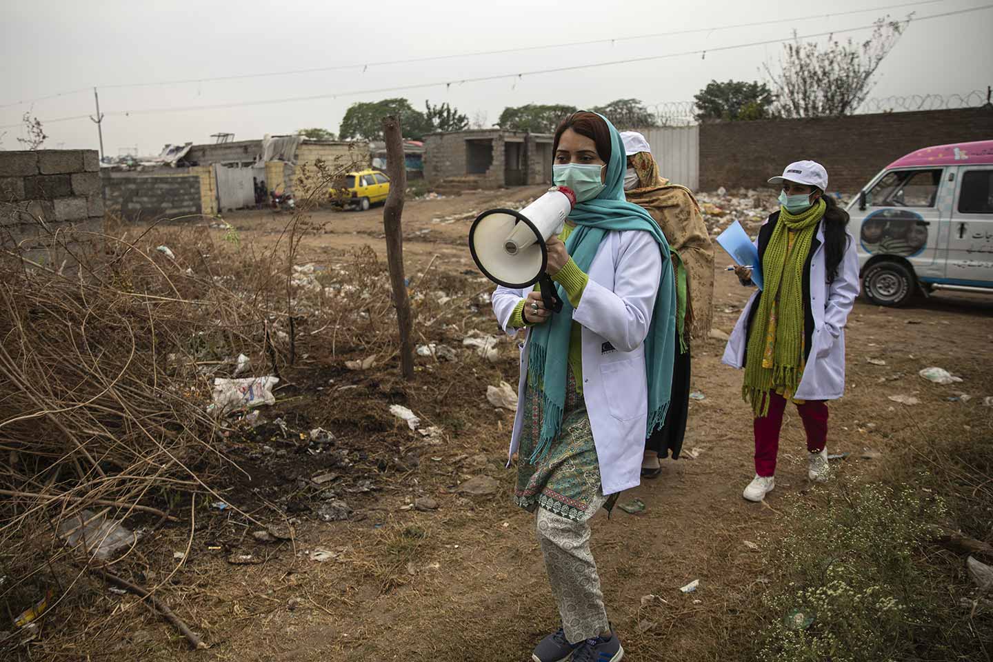 Sadaf Fareed (left) Walk towards the tented homes in slum making announcements. Credit: Gavi/2020/Asad Zaidi