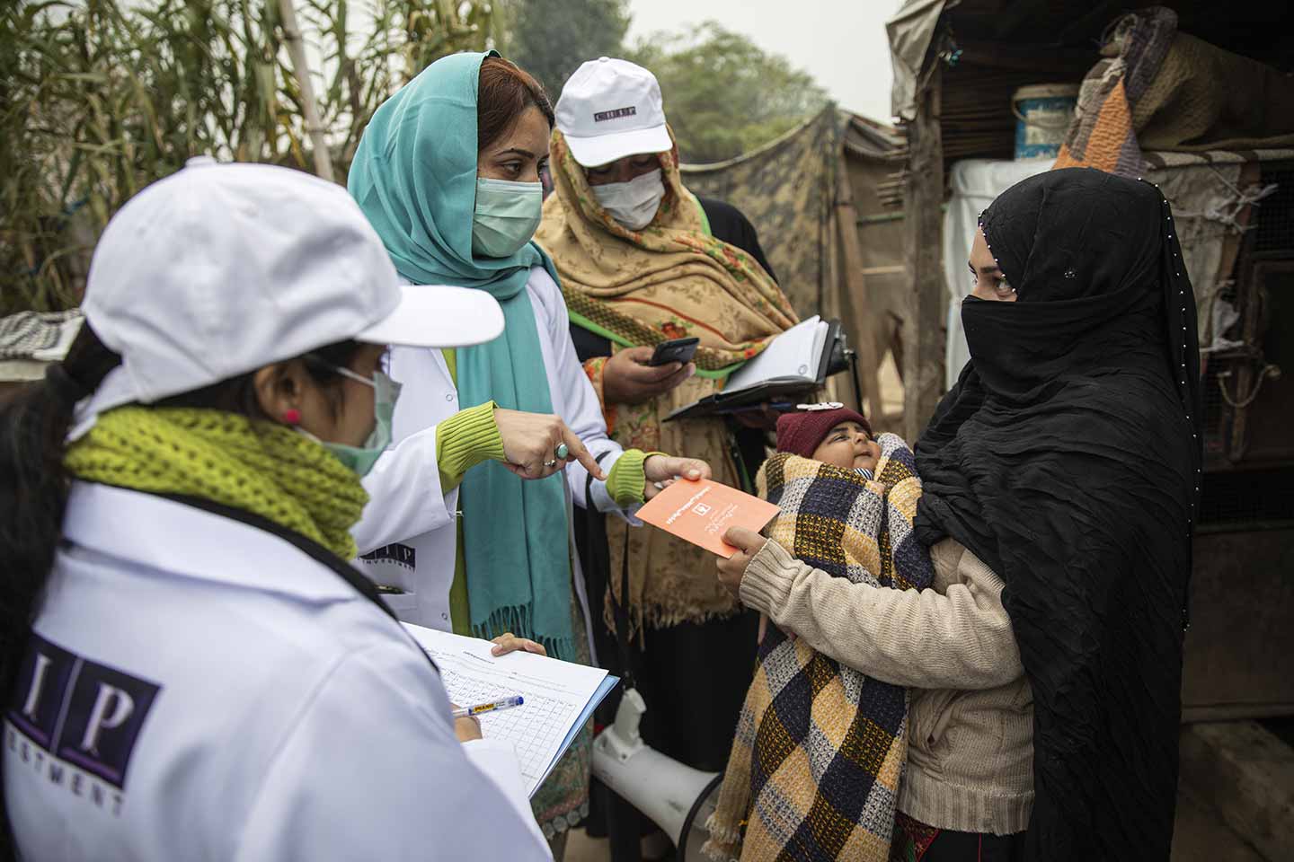 Sadaf Fareed, with her team checking the vaccination record card of a child during their field work in a slum in Islamabad Credit: Gavi/2020/Asad Zaidi