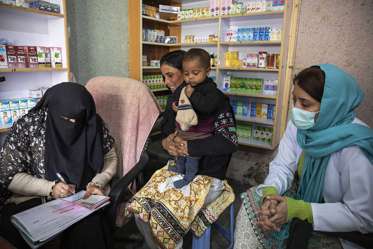 A female vaccinator after vaccinating Fakhra (zero-doze child) enters the child vaccination record in a vaccination card. Credit: Gavi/2020/Asad Zaidi 