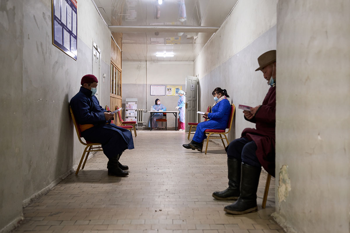 [L-R] Buyanjargal, Bolormaa and Gavaa read the vaccine brochure while they await their first jab of the COVAX Oxford-AstraZeneca vaccine