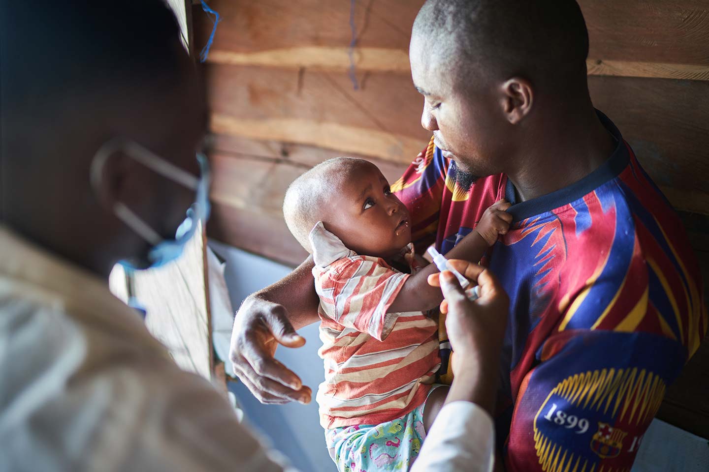 A father holding his son while he finally gets vaccinated – Gavi/2021/Christophe Da Silva