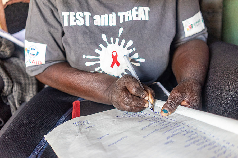 Community health worker Sithembile Ndhlovu, 51, writes down the names of residents due to receive their first dose of COVID-19 vaccine