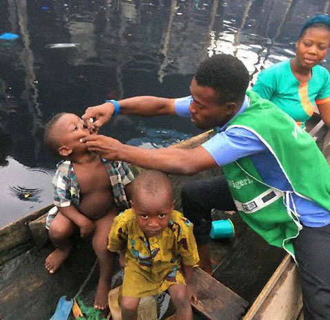 Peter Idowu administers vaccine on kids inside a canoe Credits: HEIA, Peter Idowu, Al-Jazeera