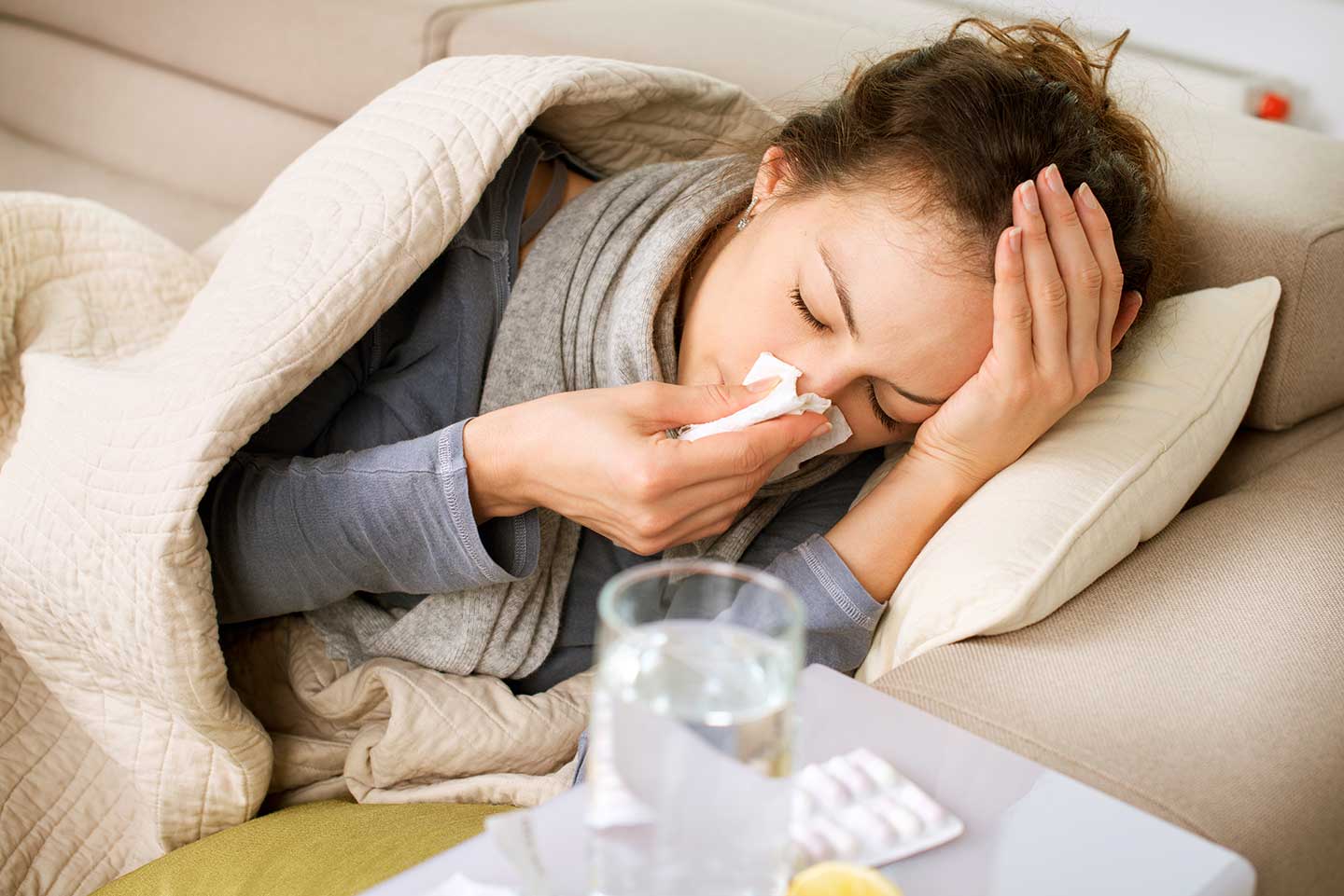 Sick woman sneezing into tissue.