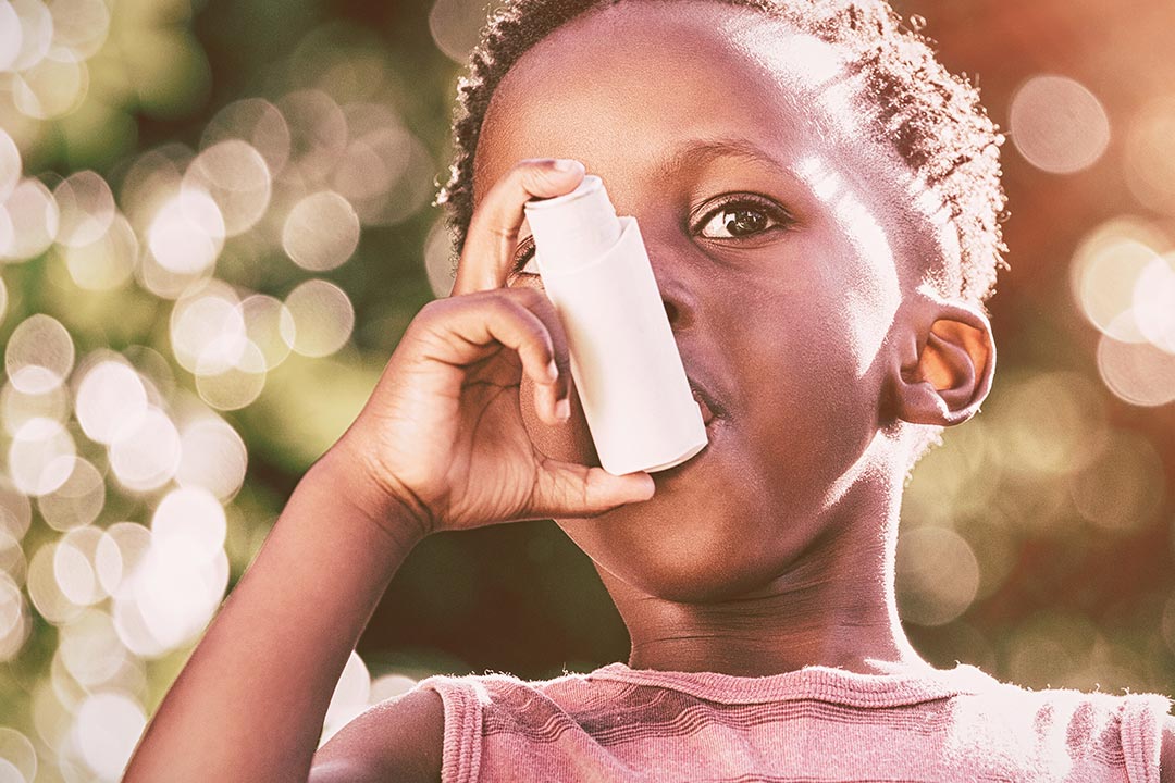 Boy using a asthma inhalator in a park