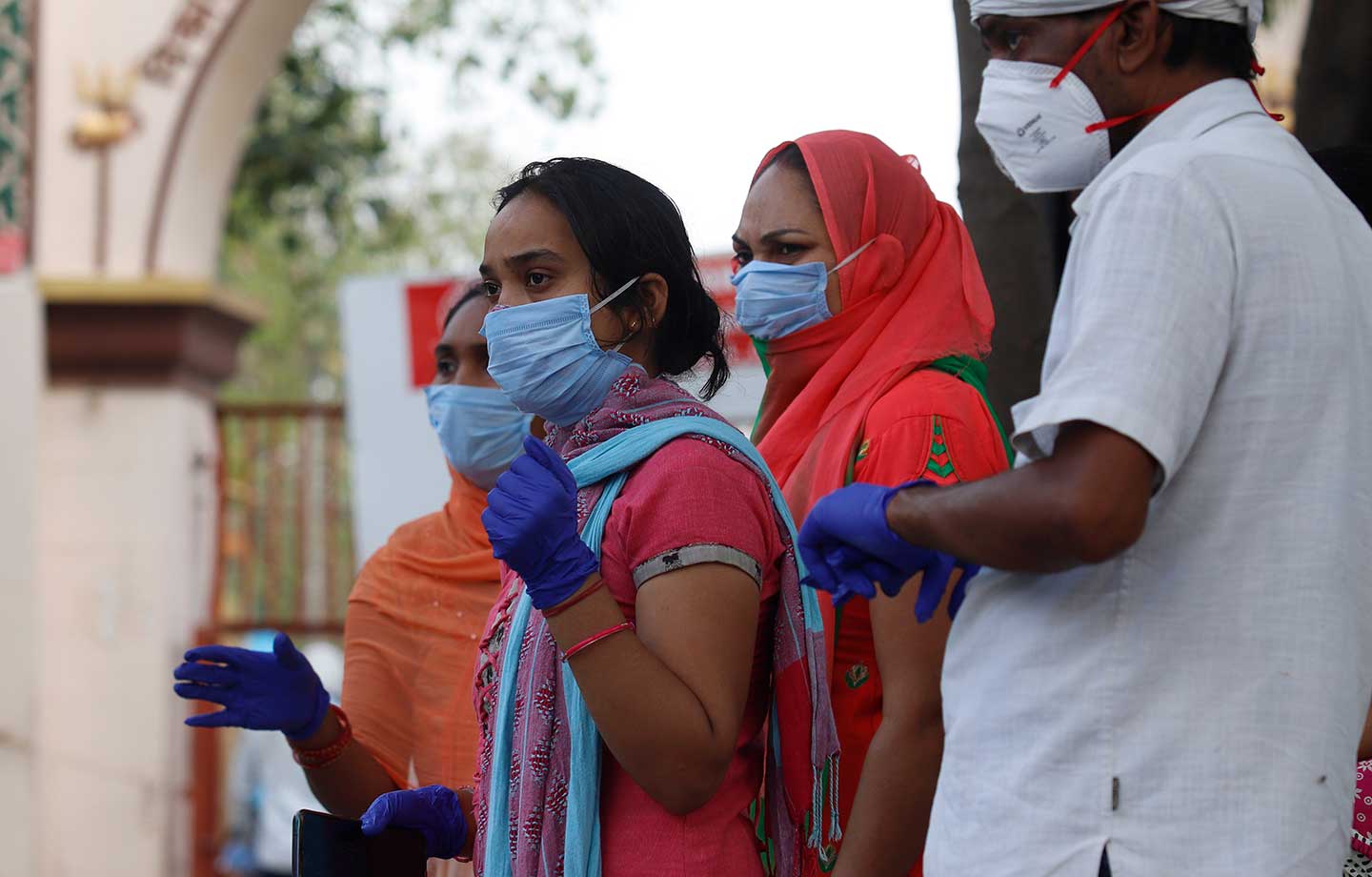Indian health workers wearing personal protective equipment (PPE) and relatives carrying the mortal remains of a COVID-19 victim at the cremation ground