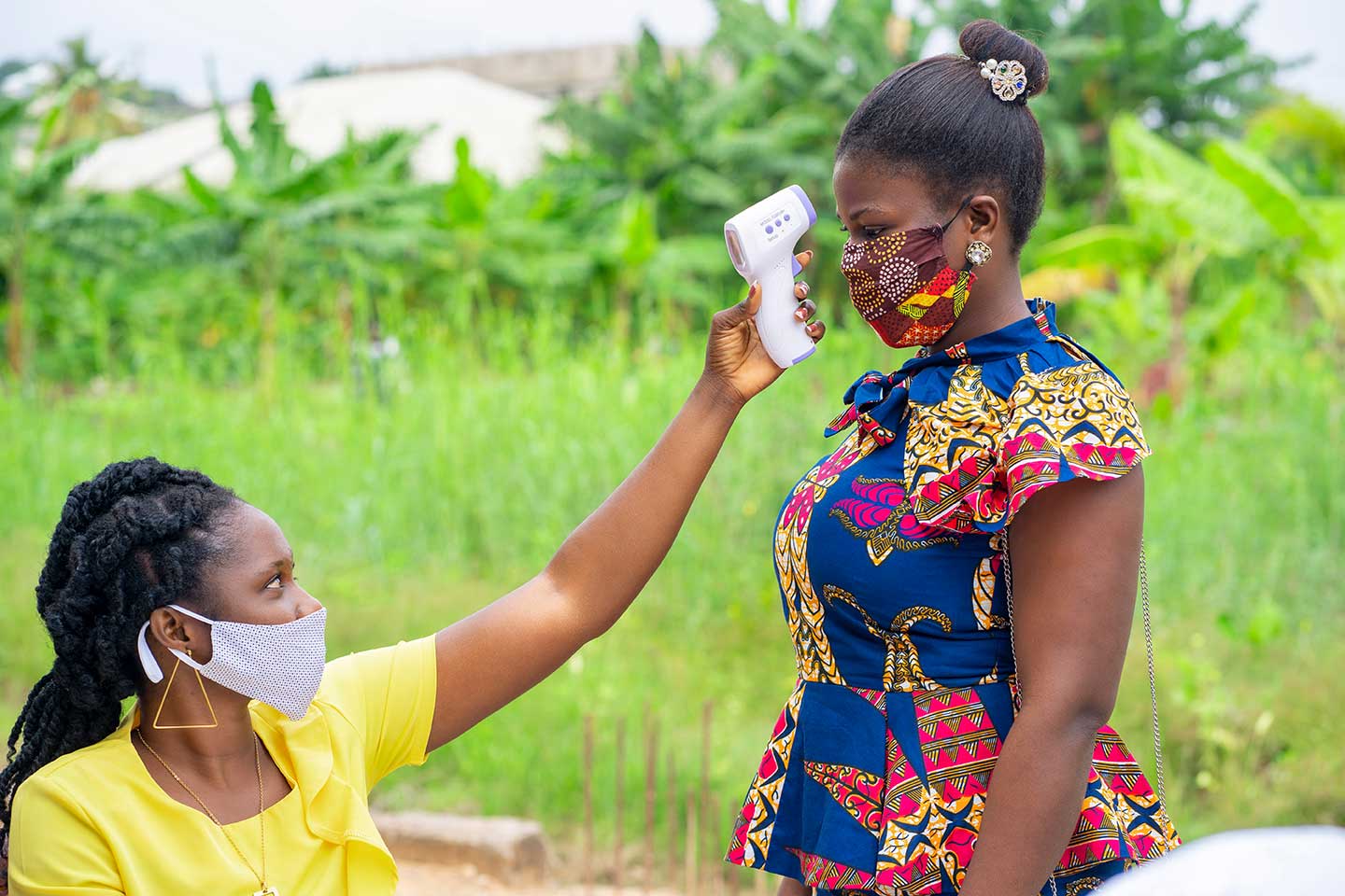 African health worker testing a lady's temperature