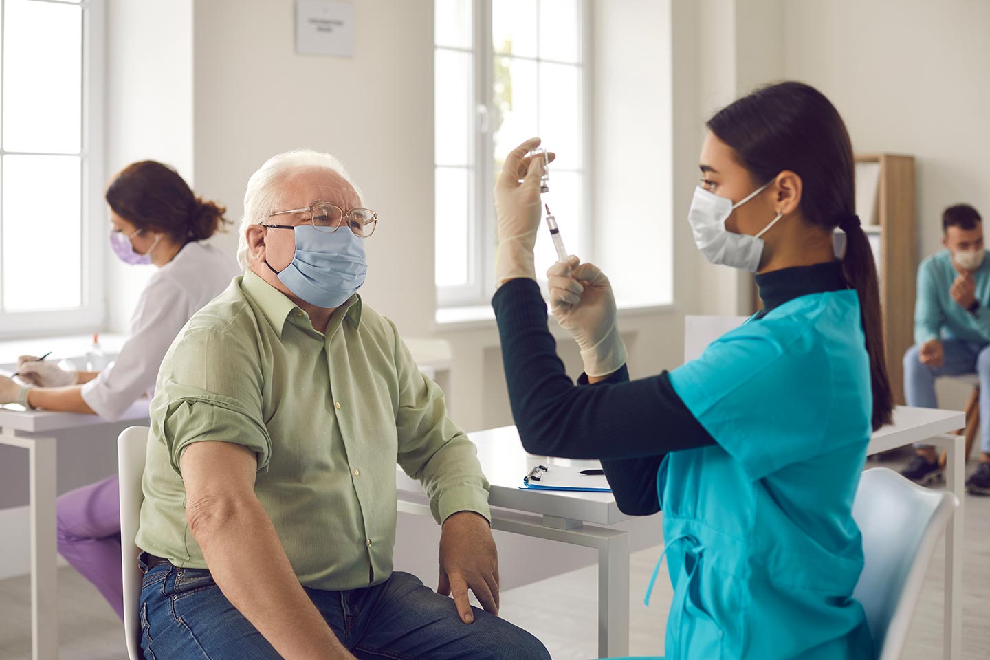 Male senior citizen waiting to receive his vaccine. Asian doctor in face mask administering shot to mature man.