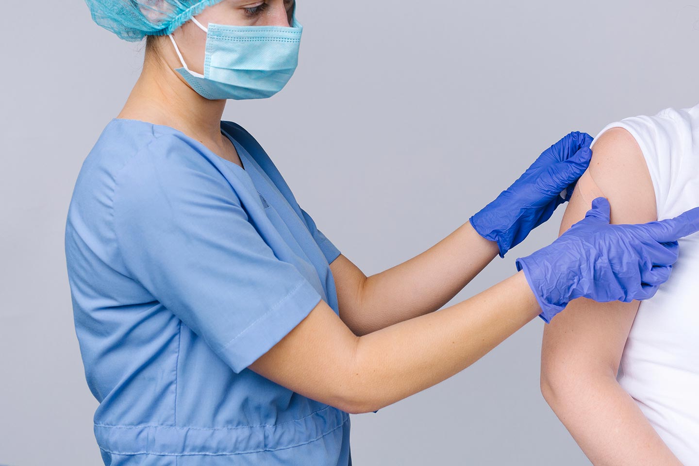 Healthcare professional putting band-aid on arm of a patient after coronavirus vaccine.