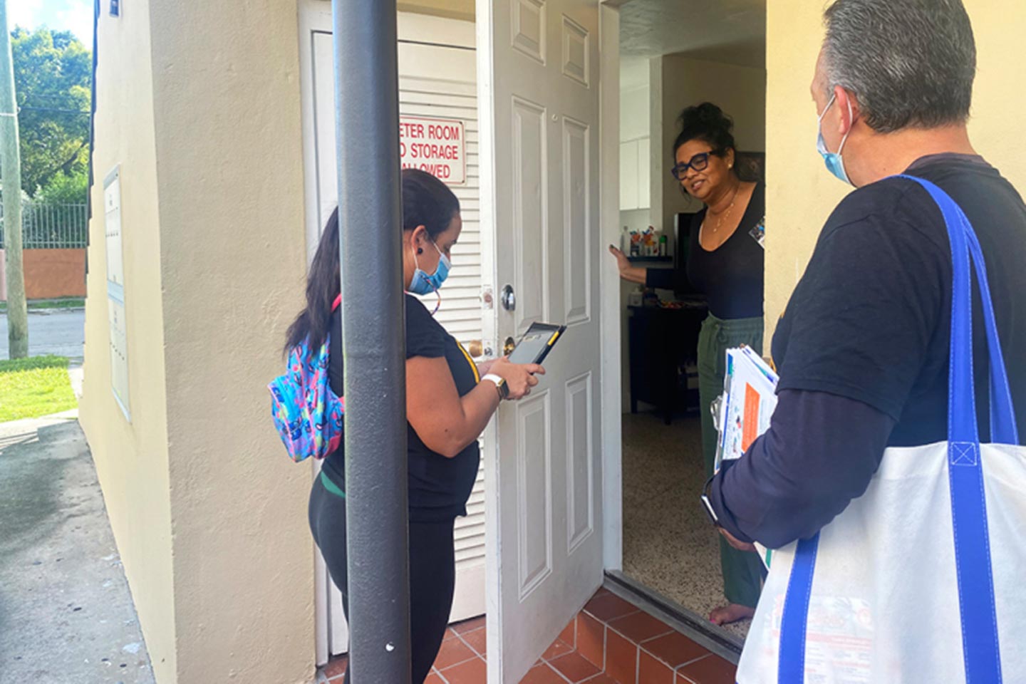 In their canvassing of a predominantly Cuban American neighborhood in October, Alejandro Díaz (right) and another community outreach worker, María Elena González (left), spoke with Gloria Carvajal about how to get a covid-19 test. (Verónica Zaragovia/WLRN)