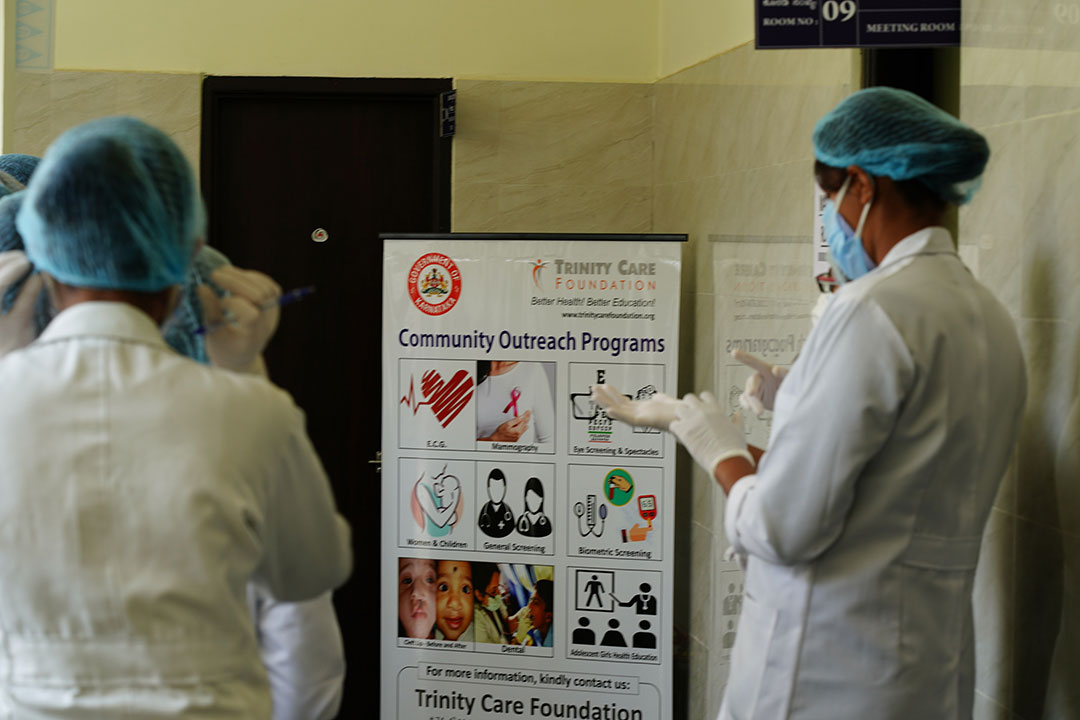 Medical personnel at Trinity Care Foundation reading a poster about community outreach on Universal Health Coverage Day amidst the COVID-19 pandemic in 2021 in rural Karnataka, India. Scientists have warned that COVID-19 will remain uncontrolled in many countries unless coordinated action is taken. Copyright: Trinity Care Foundation, (CC BY-NC-ND 2.0)