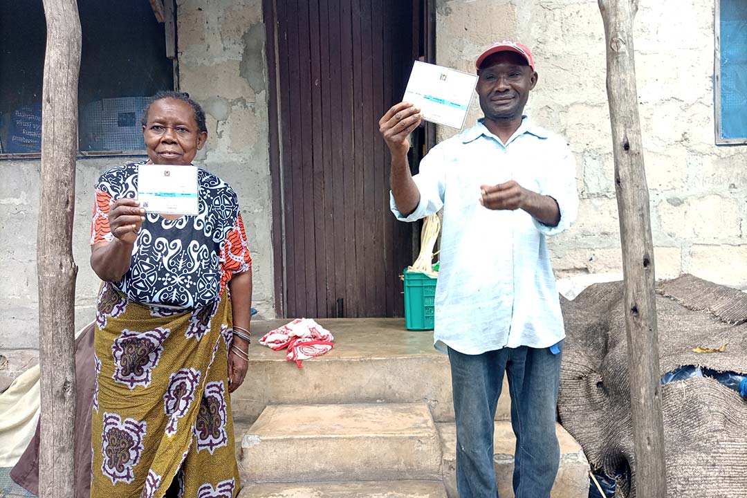 Two recently-vaccinated community members display their health cards. Credit: Syriacus Buguzi