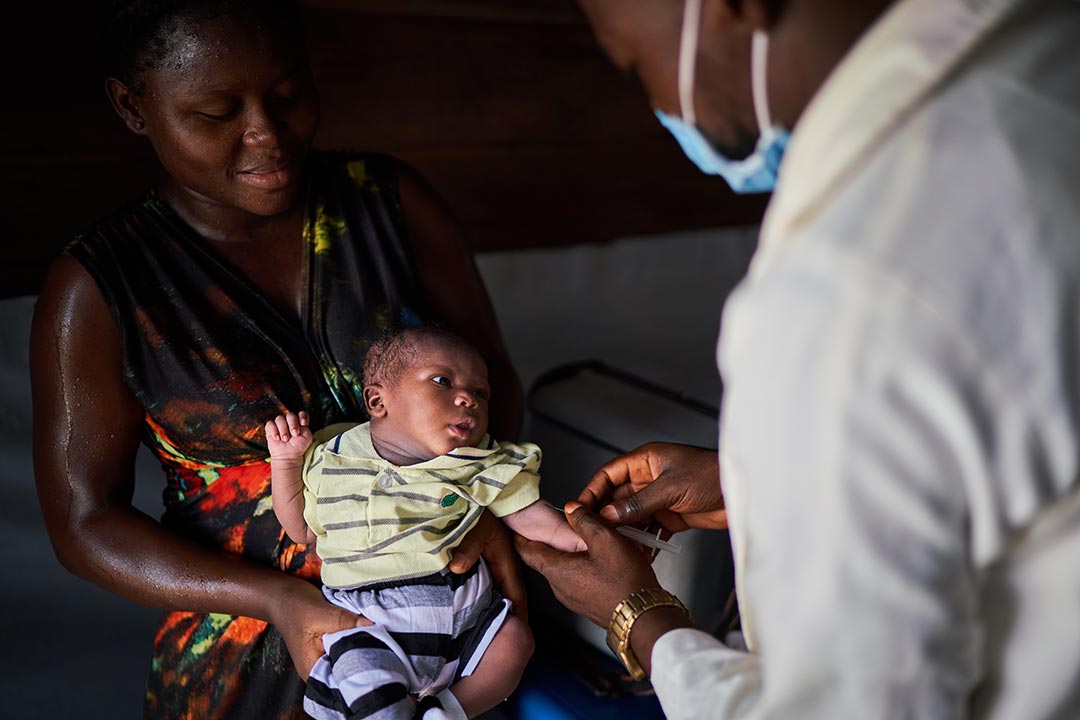 A masked health worker vaccinates an infant in Nigeria. Credit: Gavi/2021/Christophe Da Silva