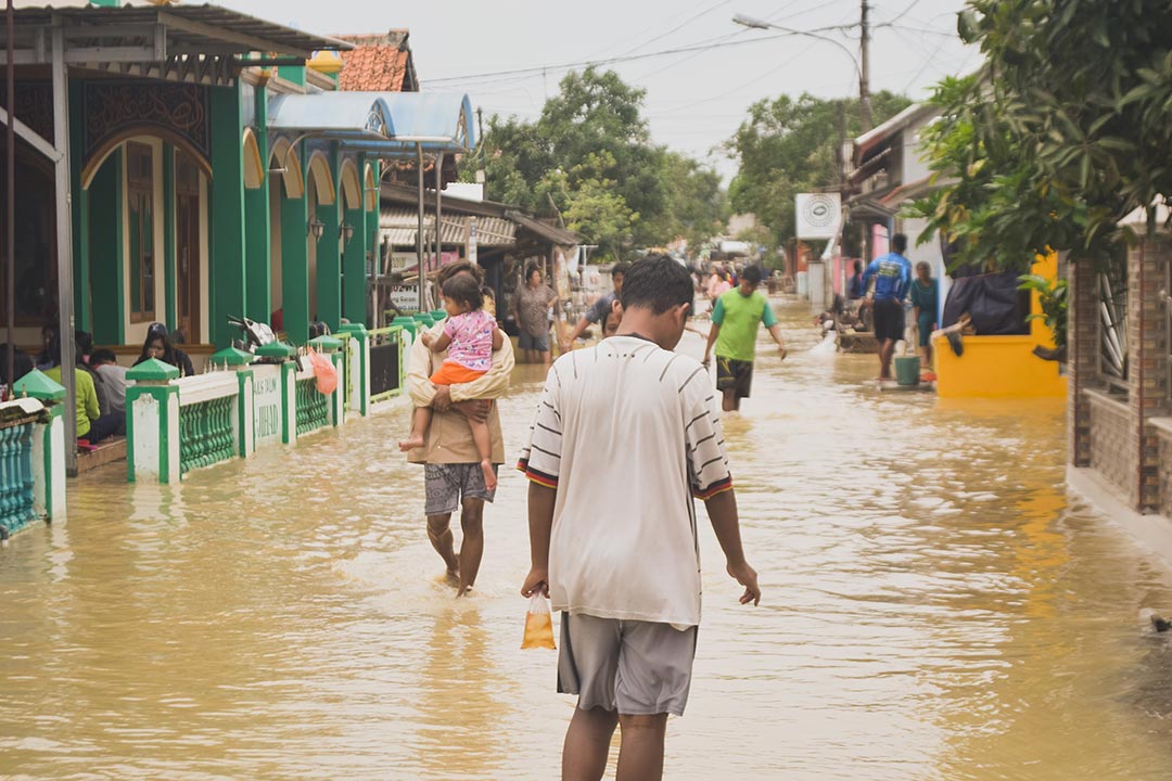 People walking in a flooded street as a result of climate change. Photo by Misbahul Aulia on Unsplash