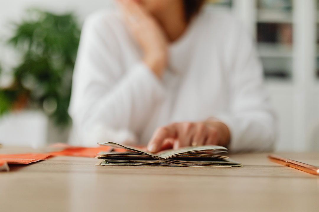 Woman sitting behind a desk and counting money and receipts. Photo by Karolina Grabowska from Pexels