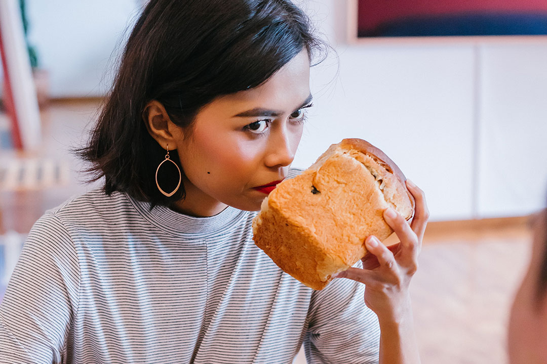 A woman trying to smell bread. Photo by mentatdgt from Pexels