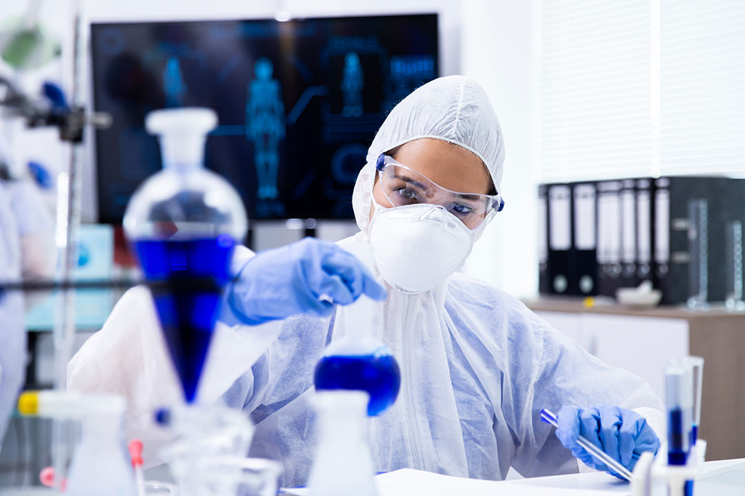 Researcher in full protective equipment in a lab.