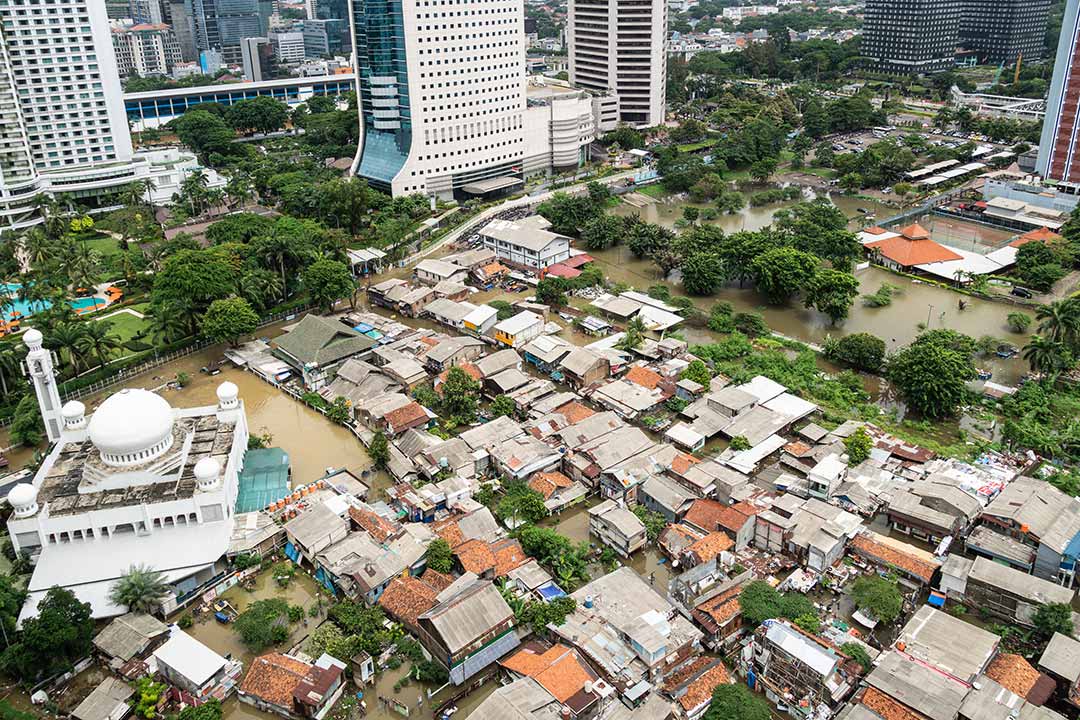 The flooded street in a poor residential district showing huge inequalities with modern towers surrounding it.