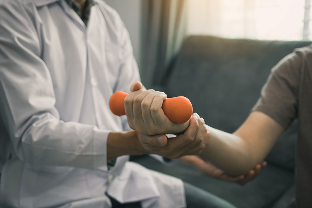 A physiotherapist helping patient with lifting dumbbells exercises.