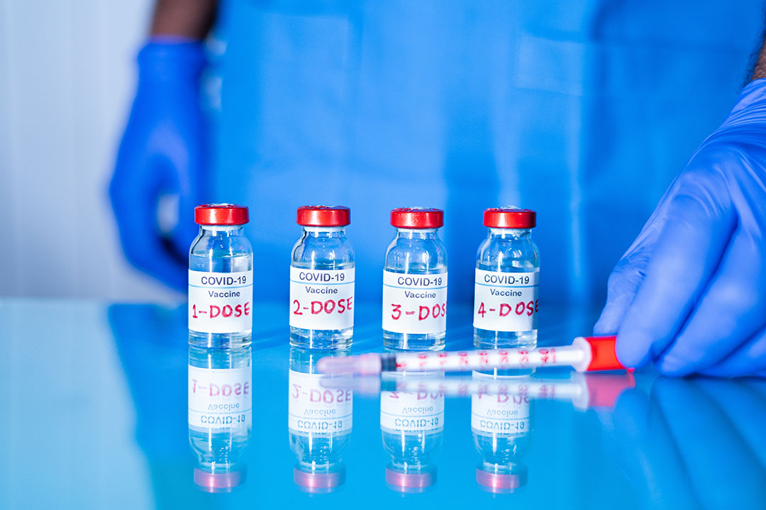 Close up of doctor placing multiple doses of COVID-19 vaccines and syringe on table for vaccination to protect against the variants and stop the pandemic.