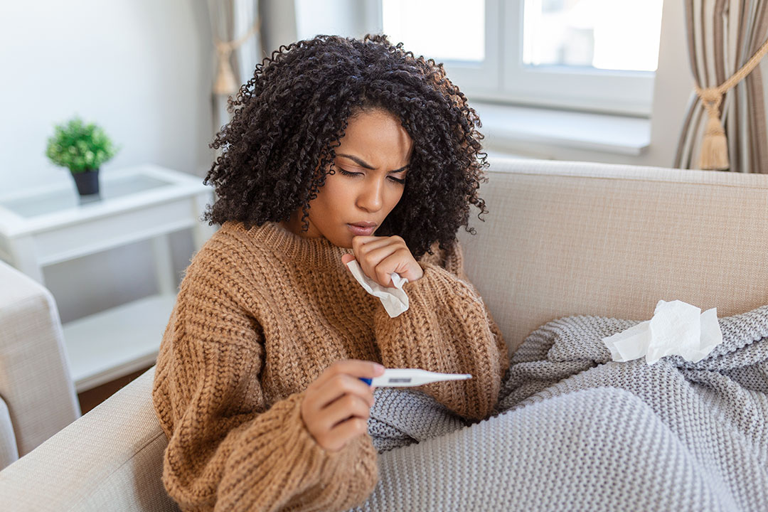 Young woman, sick at home checking her temparature.