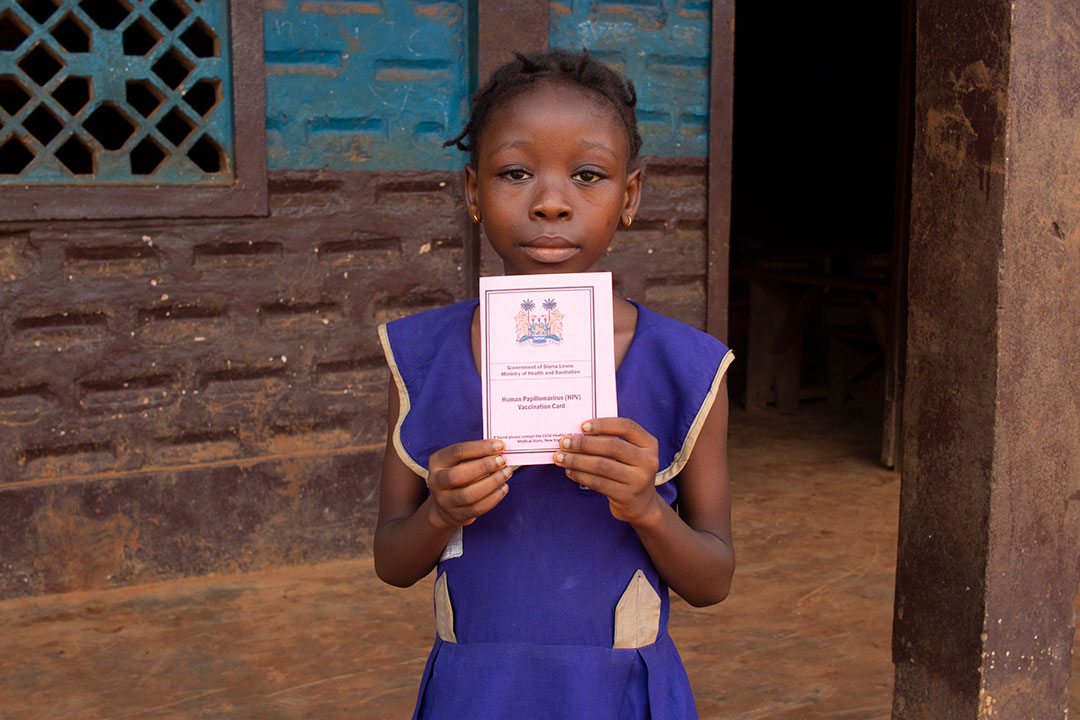 A girl at War Wounded Primary School in Grafton, Freetown, holds up her vaccination card. Credit: Abdul Aziz Kamara