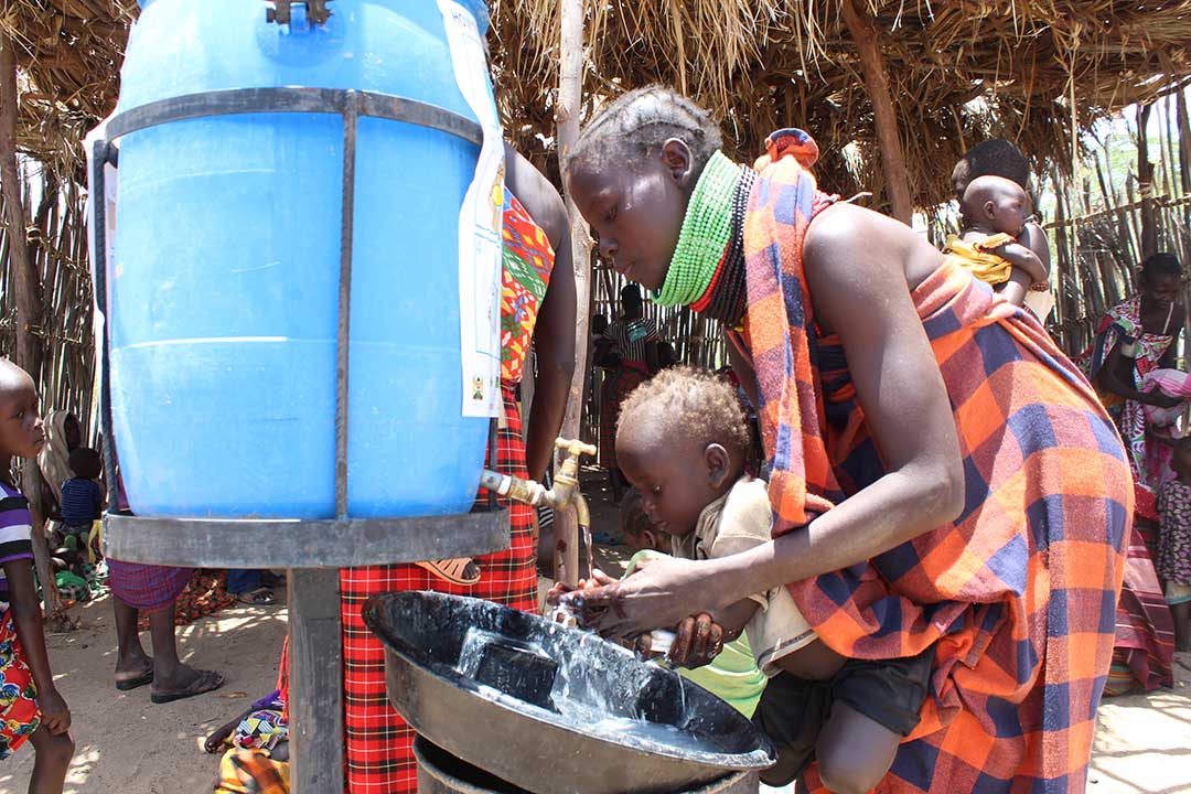 Hellen Kuwom, a resident of Nangolpus in Turkana Central, washing the hands of her child to curb the spread of COVID-19. Credit: Abjata Khalf