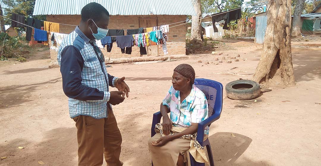 Laban sharing a verified message from the WHO website with an elderly woman at Adagom 1 refugee settlement camp Ogoja, Cross River State, Nigeria. Photo Credit: Ijeoma Ukazu
