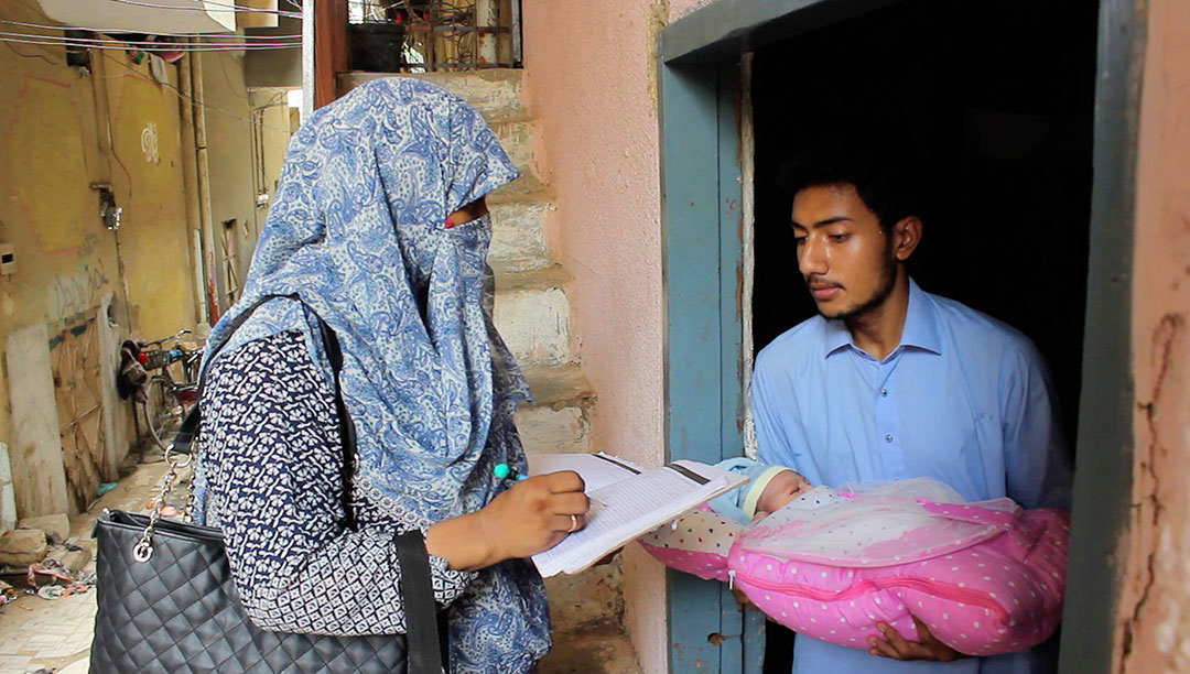 A Community Health Worker goes door to door during the August polio campaign to give children the oral polio vaccine. She finds a newborn zero-dose child and records that data into her register. Credit: @SalmanMahar