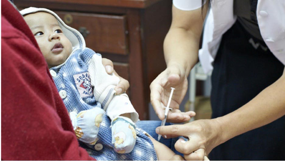 Nurse Manokra Khamsai administers measles vaccine jab to a young baby. Credit Nittana Ketkeson